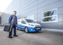 Empleado de Blueserv con una caja de herramientas delante de un coche Blueserv de marca